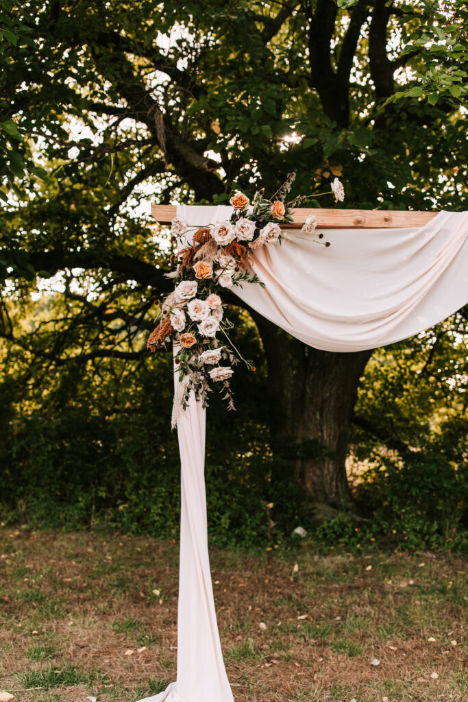 The ceremony arch covered with florals and white draping fabric. This is an example of wedding detail shots.