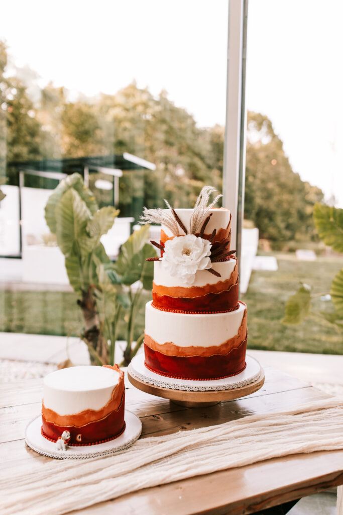 Large and small wedding cake with rust accents done in a western style at a wedding at Greenhouse Two Rivers.