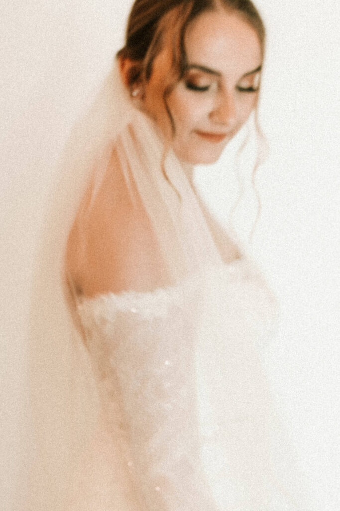 A bride glances down at the floor photographed in the blurry wedding photo trend.