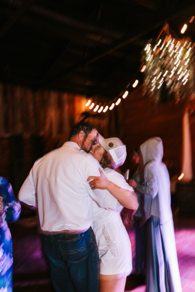 Bride hugs her groom at their wedding reception. The dim light and motion create the blurry wedding photo trend. 