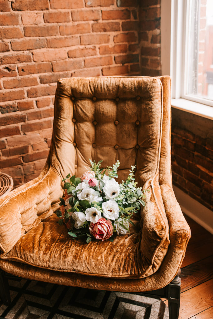 Rust velvet chair holding a bridal bouquet at a wedding in Springfield, Missouri photographed by Bailey Morris.
