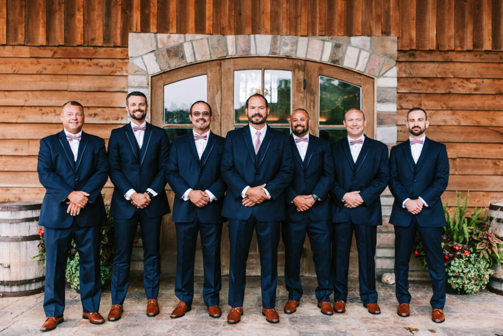 Groomsman in front stone arch and wooden door in Lebanon Missouri. Wedding photography by Bailey Morris.