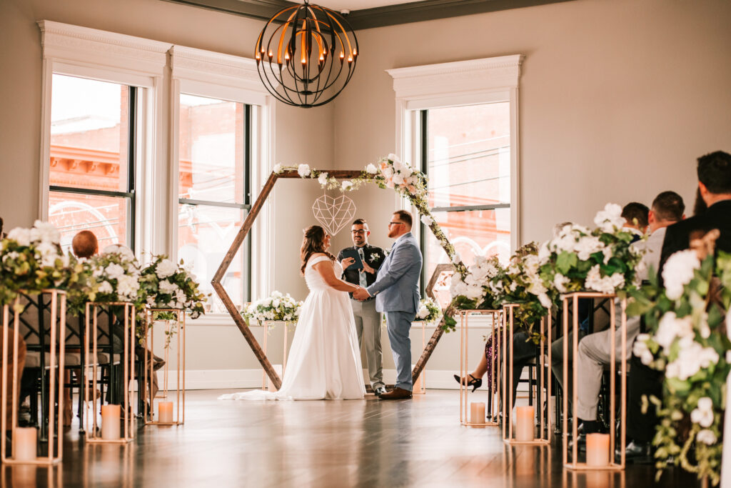 Couple getting married under their hexagon shaped archway at a Hotel Vandivort wedding in Springfield, Missouri photographed by Bailey Morris photography during the spring wedding season.