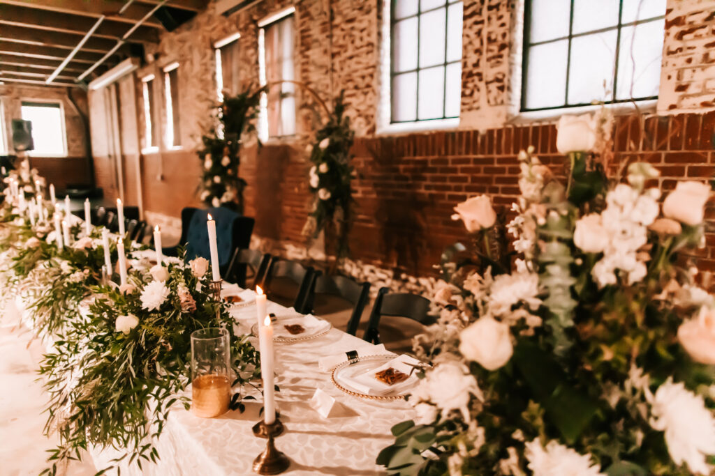 Stunning florals by Turner Flowers at an Ottawa, Kansas wedding reception photographed by Bailey Morris.There are white candles with gold and brass accents on the table.
