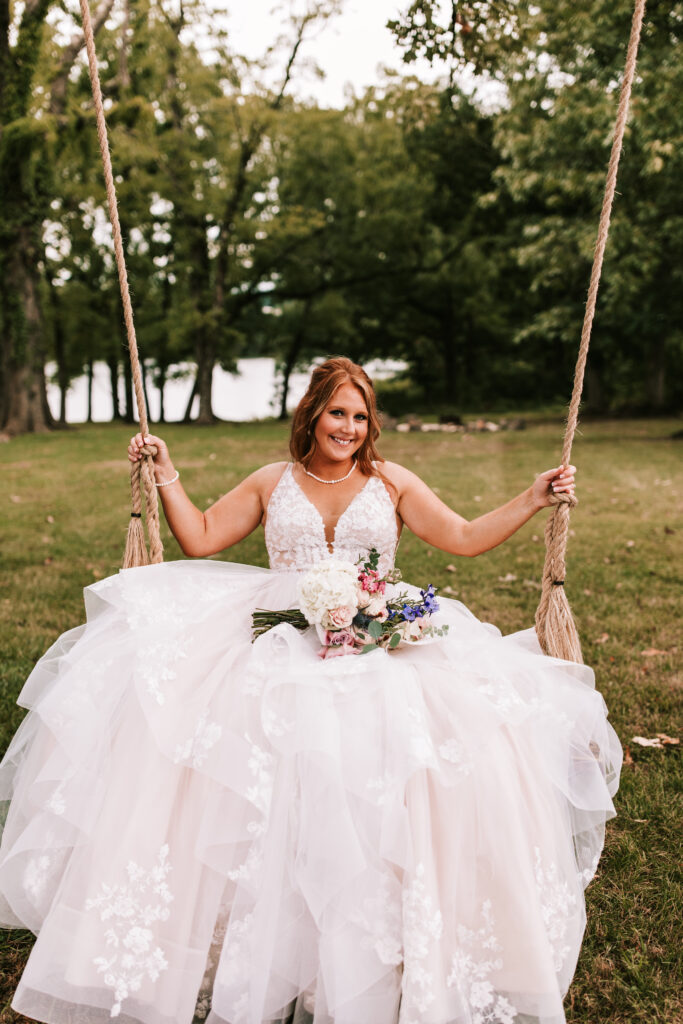 Bride swinging on the tree swing at Mighty Oak Lodge with her bouquet in her lap. 