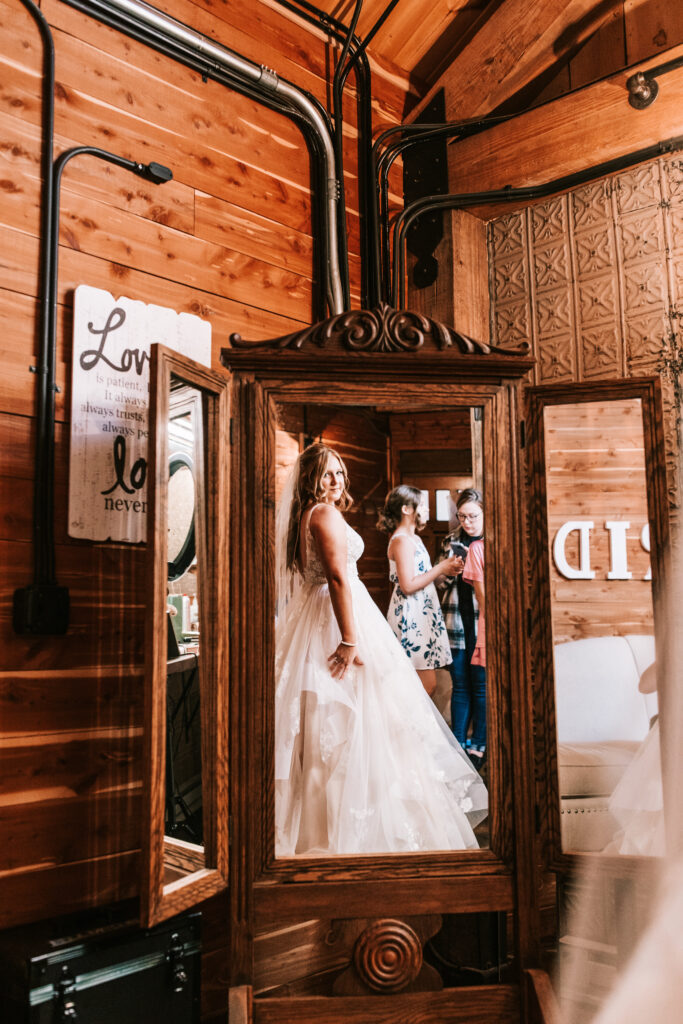 Bride looking at her reflection in the mirror in the bridal suite at Mighty Oak Lodge in Lebanon Missouri.