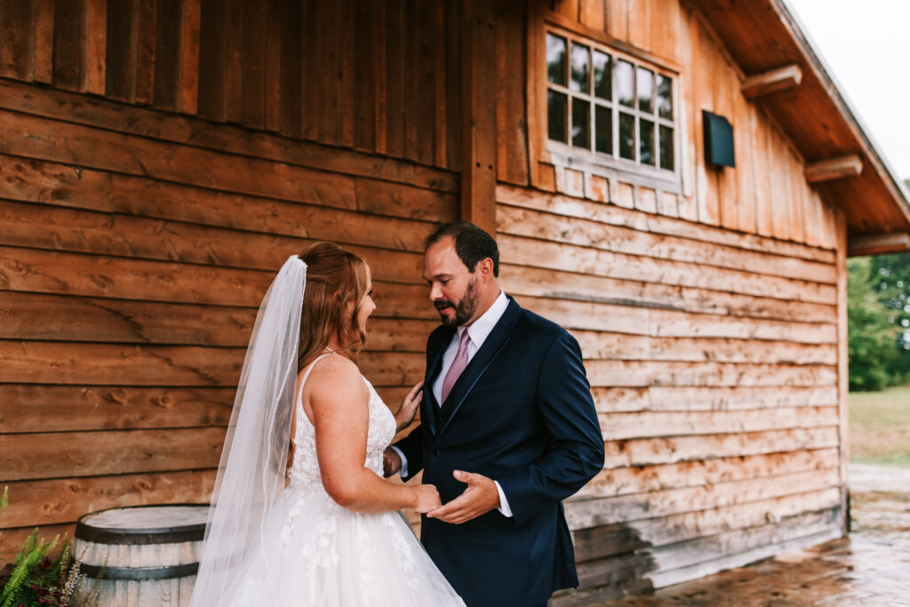 Bride and groom having their first look in front of the barn at Mighty Oak Lodge in Lebanon Missouri. 