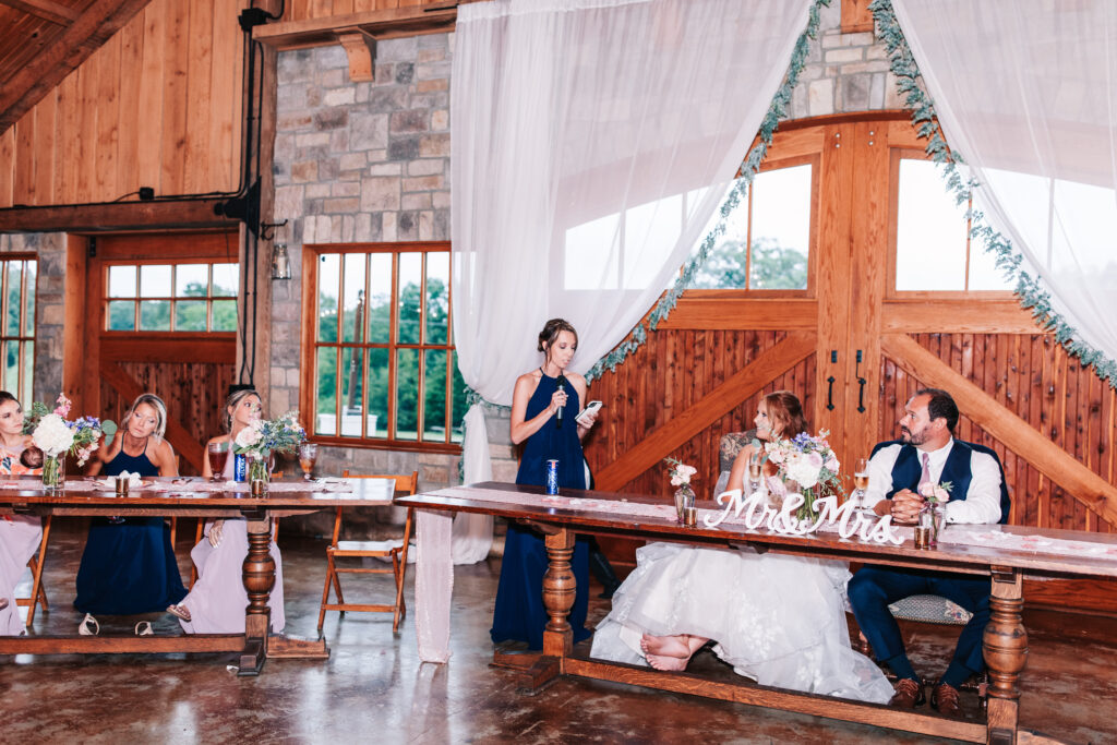 Maid of honor giving her speech at the head table at a wedding reception in Mighty Oak Lodge in Lebanon, Missouri.