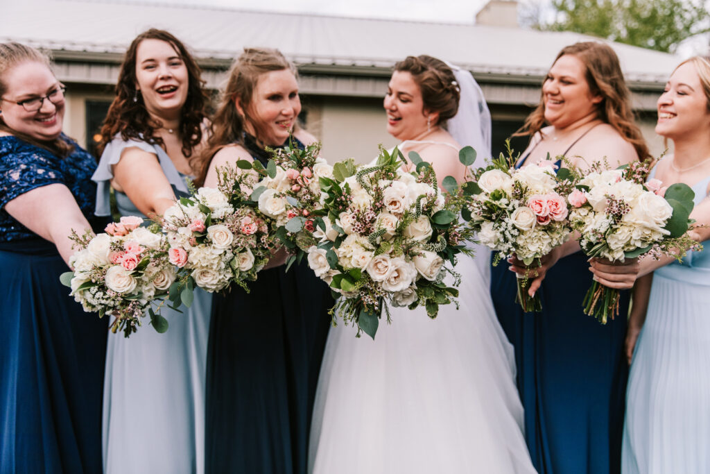 A bride and bridesmaid showing off their bridal bouquets for the spring wedding season photographed by Bailey Morris.
