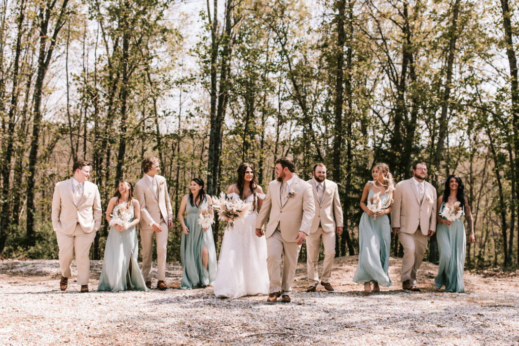Wedding party walking through the woods in a spring season wedding color palette.
