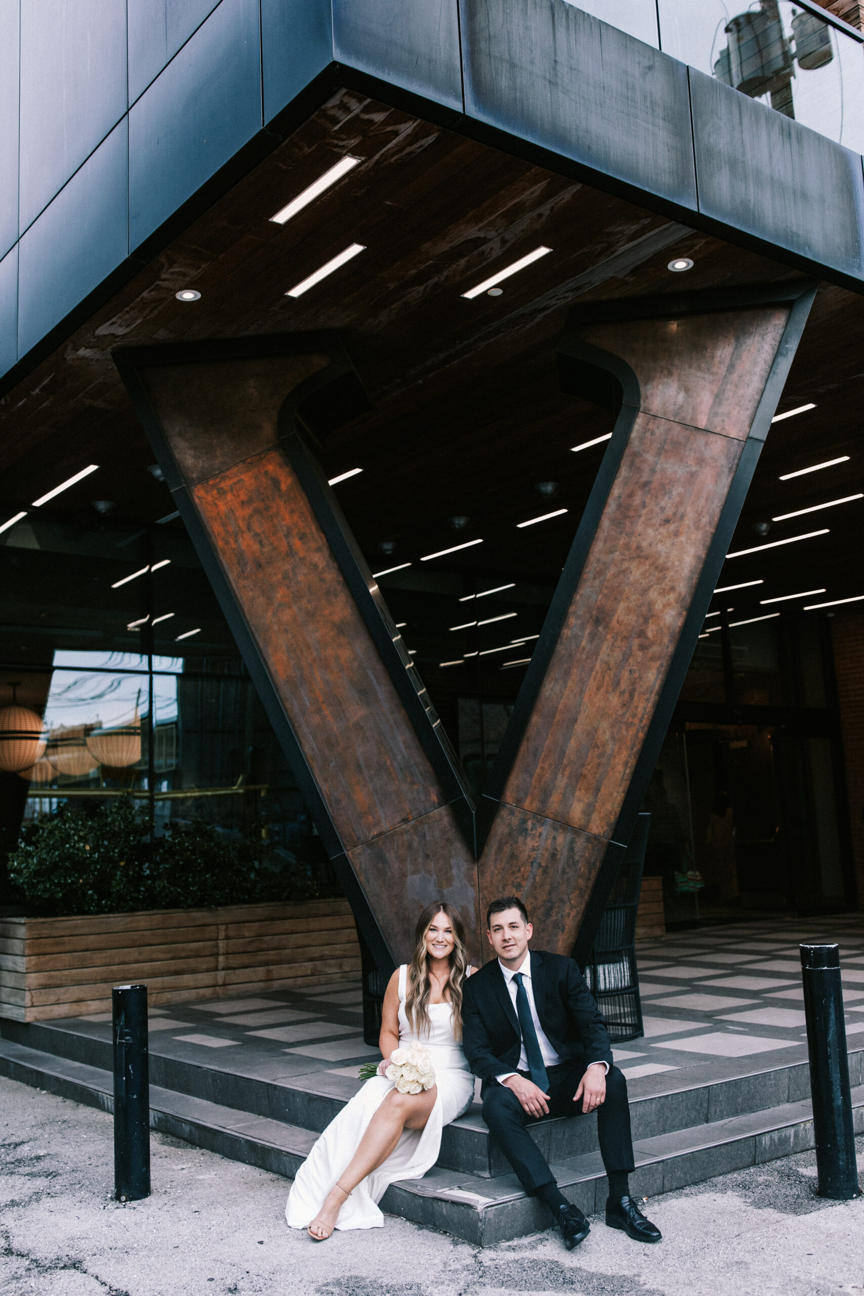 Bride and Groom sitting on steps outside of their ceremony at Hotel Vandivort.