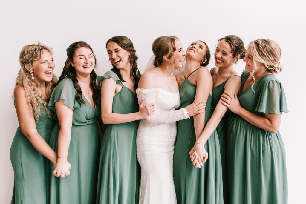 Bride with her bridesmaids at The Atrium in Branson, Missouri. Bridesmaids are wearing green dresses. Photographed by Bailey Morris wedding photography.