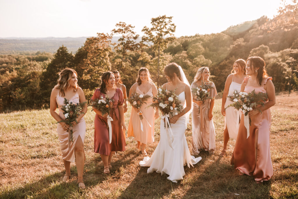Bride and her bridal party against the rolling hills of the Branson landscape at The Atrium Wedding Venue. Photo by Missouri wedding photographer Bailey Morris.