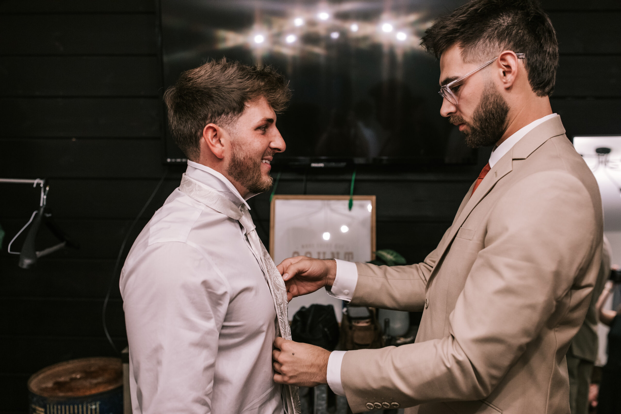 Groom and groomsman getting ready in a groom suite at a Missouri wedding venue. Photo by Bailey Morris Wedding Photography.