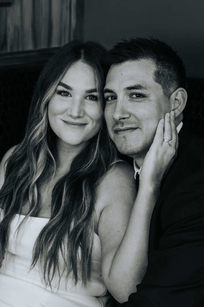 A bride has her hand on the side of the face of her groom at their wedding at Hotel Vandivort in Springfield, Missouri. Black and white wedding photos by Bailey Morris.