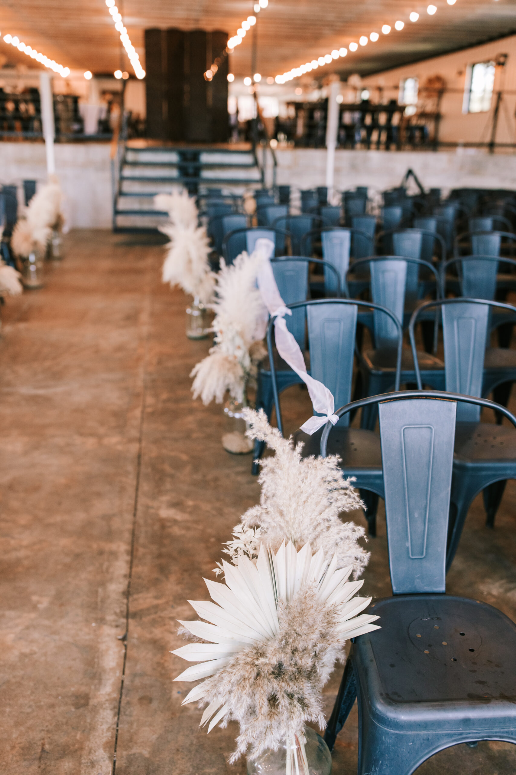 Missouri wedding venue set up with black metal chairs and unique floral arrangements lining the aisle. Wedding photographer Bailey Morris.