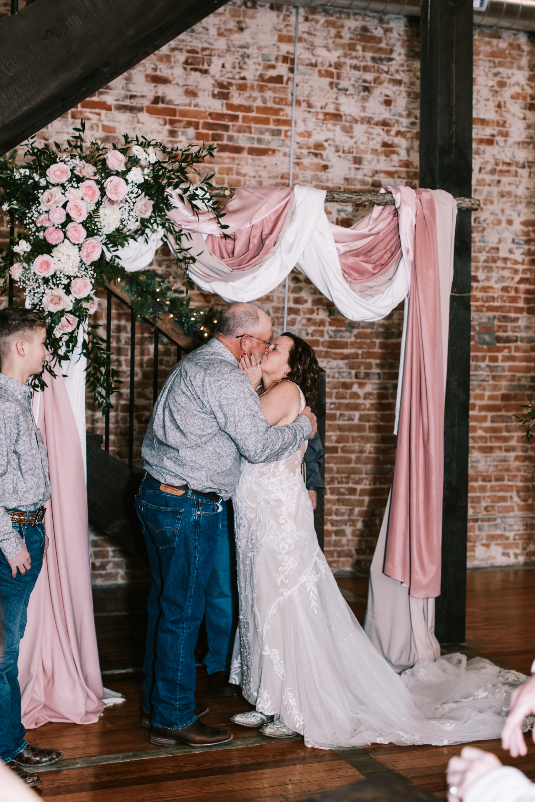 A bride and groom kissing at the end of wedding ceremony at a Missouri wedding. Photography by Bailey Morris.
