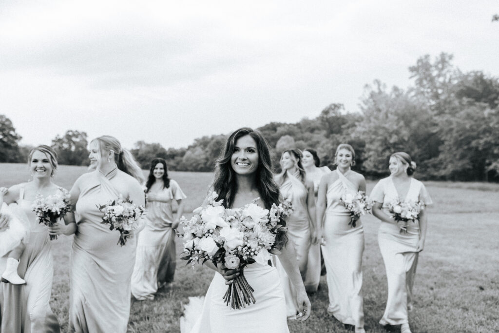 black and white photo of a bride leading her bridal party through a field in Jefferson City Missouri