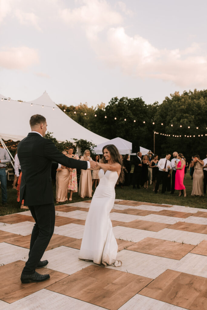 Bride and groom on a checkered dance floor at a wedding in Jefferson City Missouri on a farm. Photo by Bailey Morris.