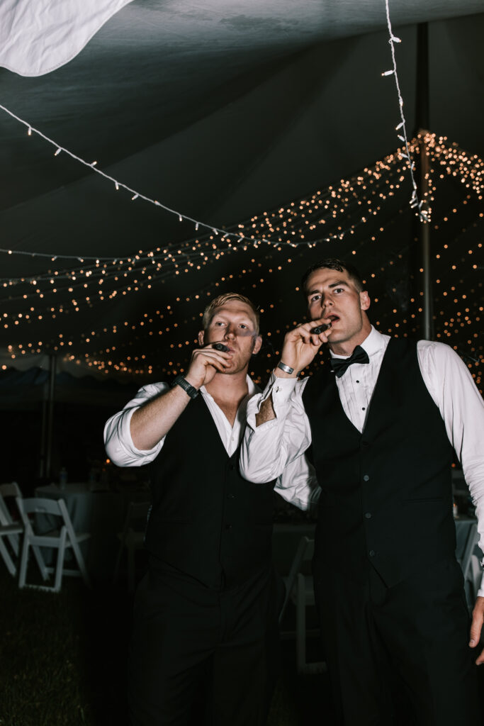 Groom and friend smoking a cigar in Jefferson City Missouri at a wedding on private property. Photo by Bailey Morris Wedding Photography. 