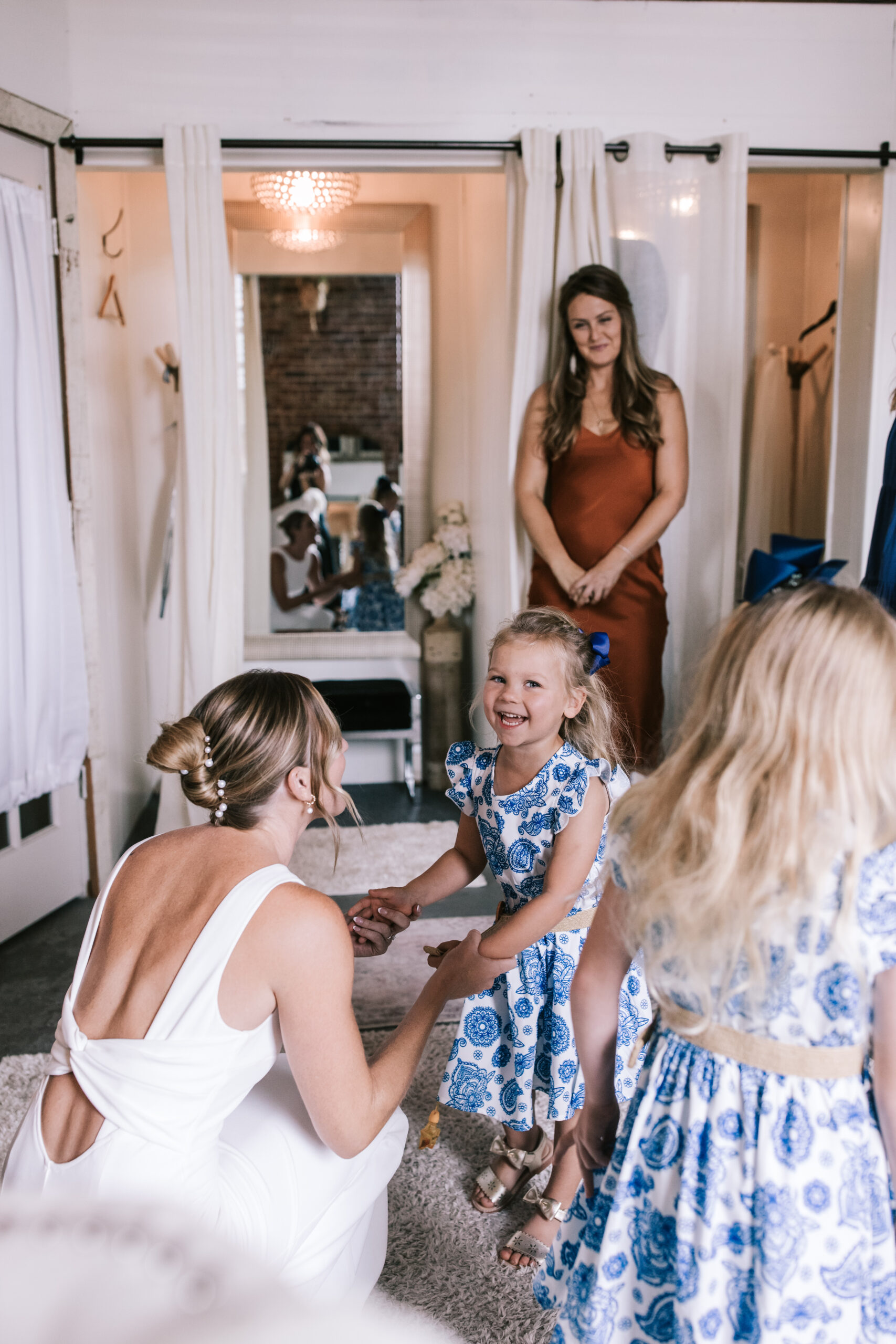 Bride holds hands of flower girl in a blue and white floral dress in the bridal suite of Venue on Brick.