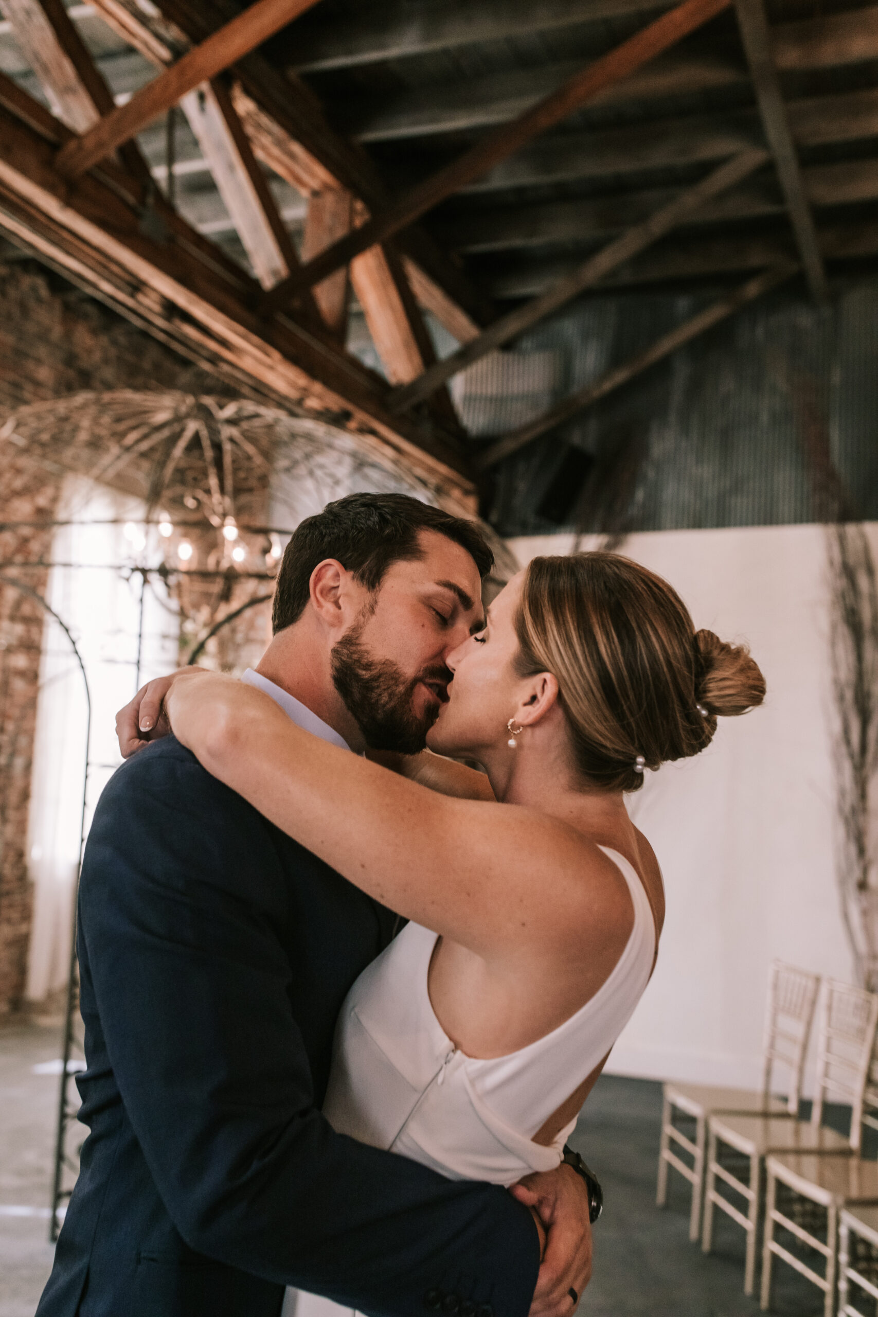 bride and groom kiss under exposed wooden beams 