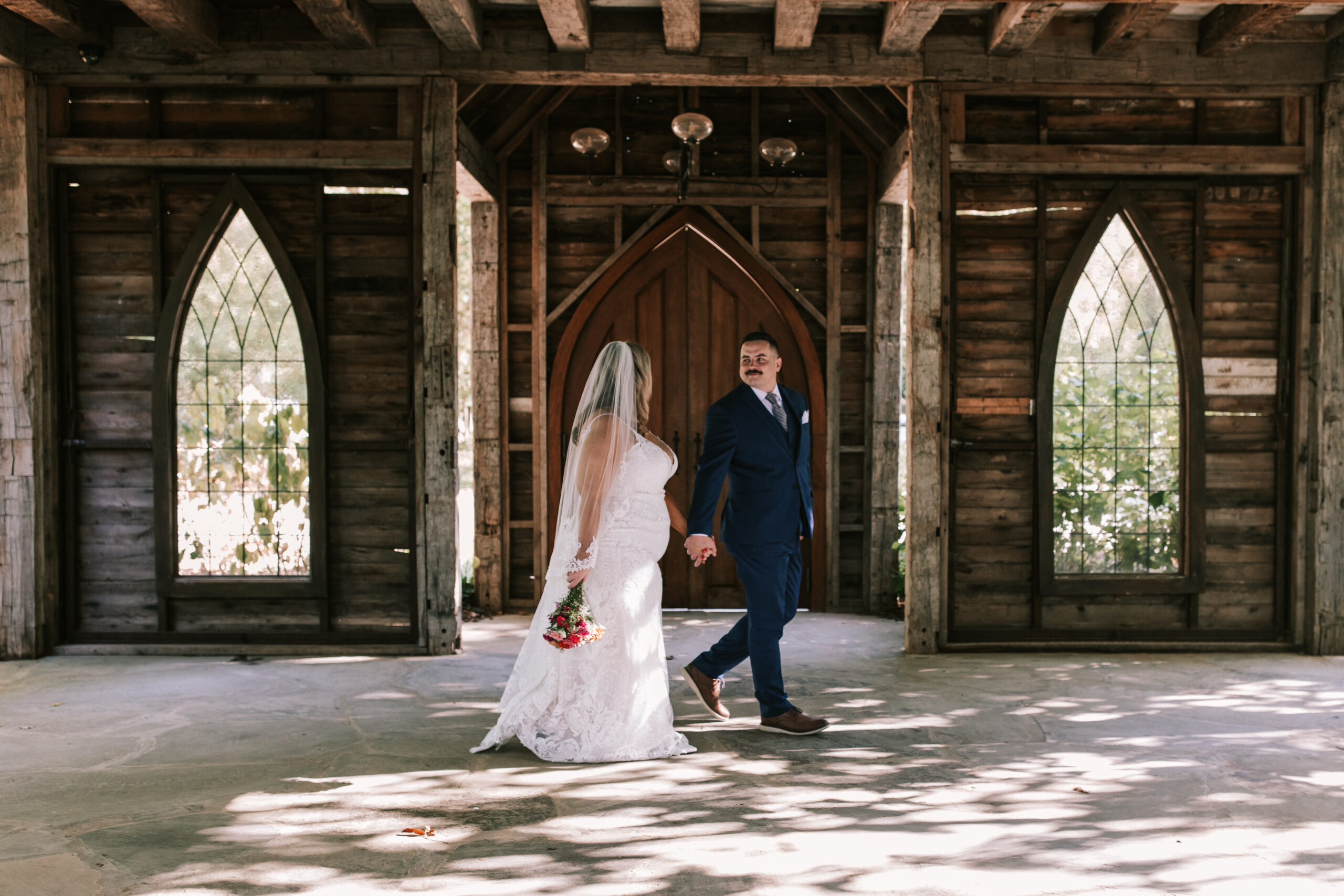 Bride and groom hold hands as they walk through The Chapel at their Finley Farms wedding.