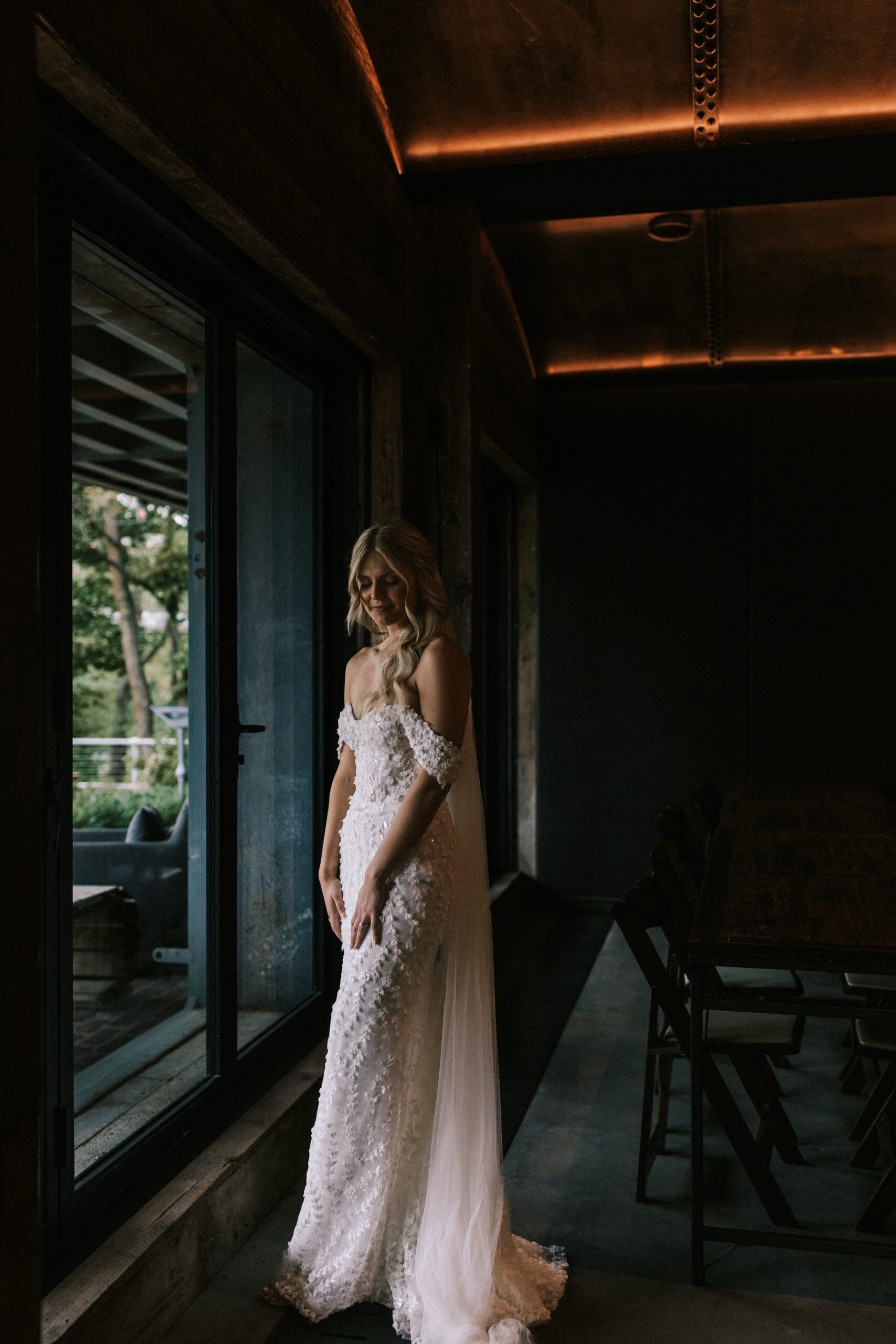 Bride in her gown looking out a window at Finley Farms wedding venue. 