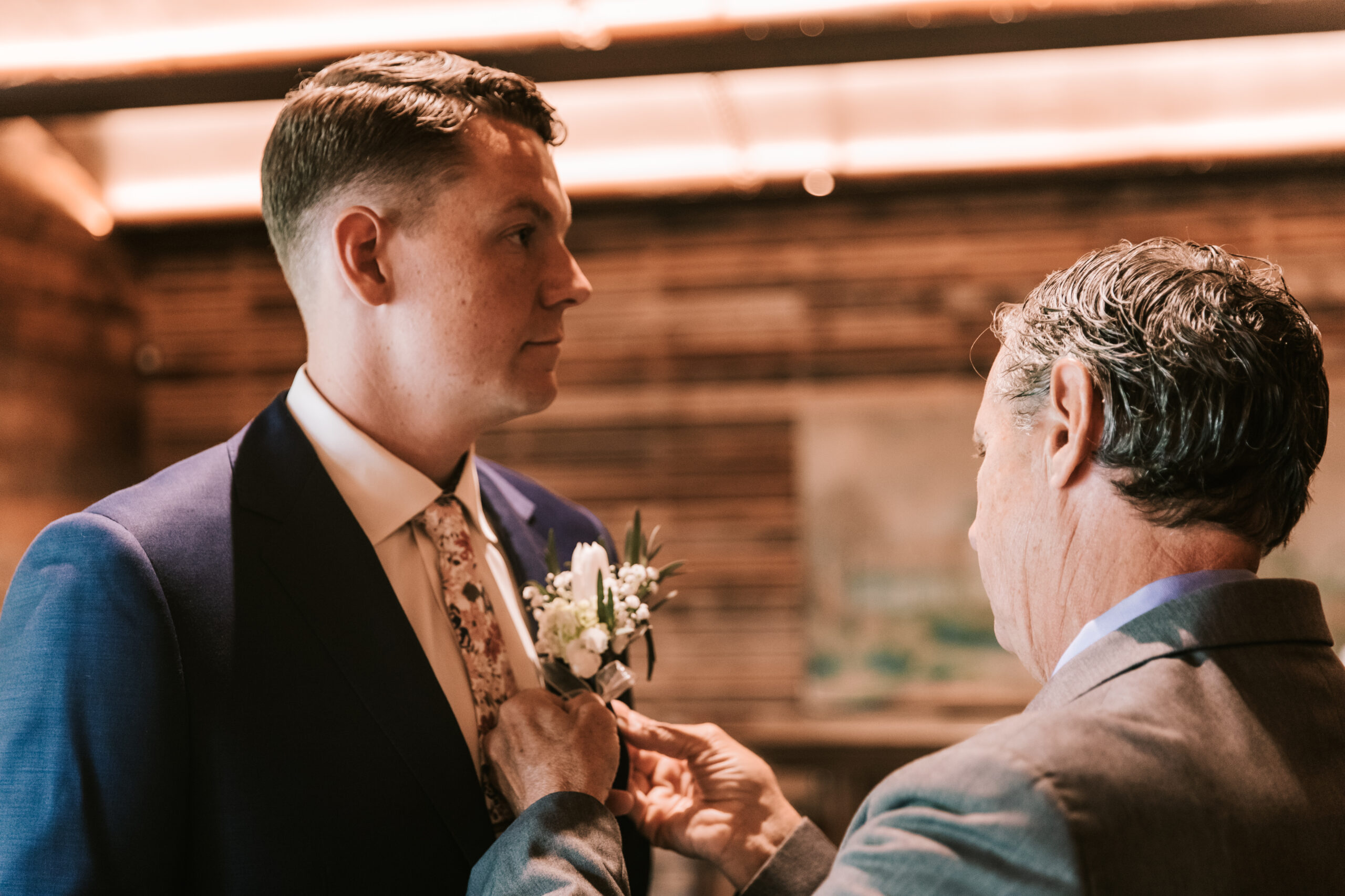 Groom gets his boutonniere adjusted by his father before his wedding at Finley Farms wedding venue. 