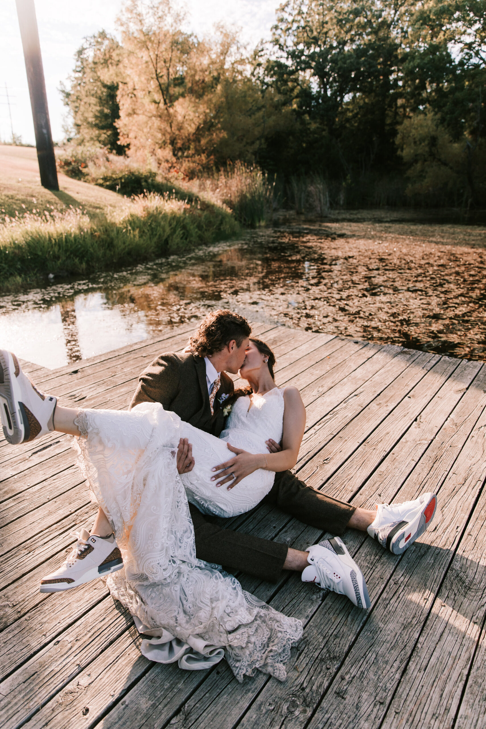 Newly married couple kisses on a dock near the lake at Mighty Oak Lodge in Lebanon, Missouri.